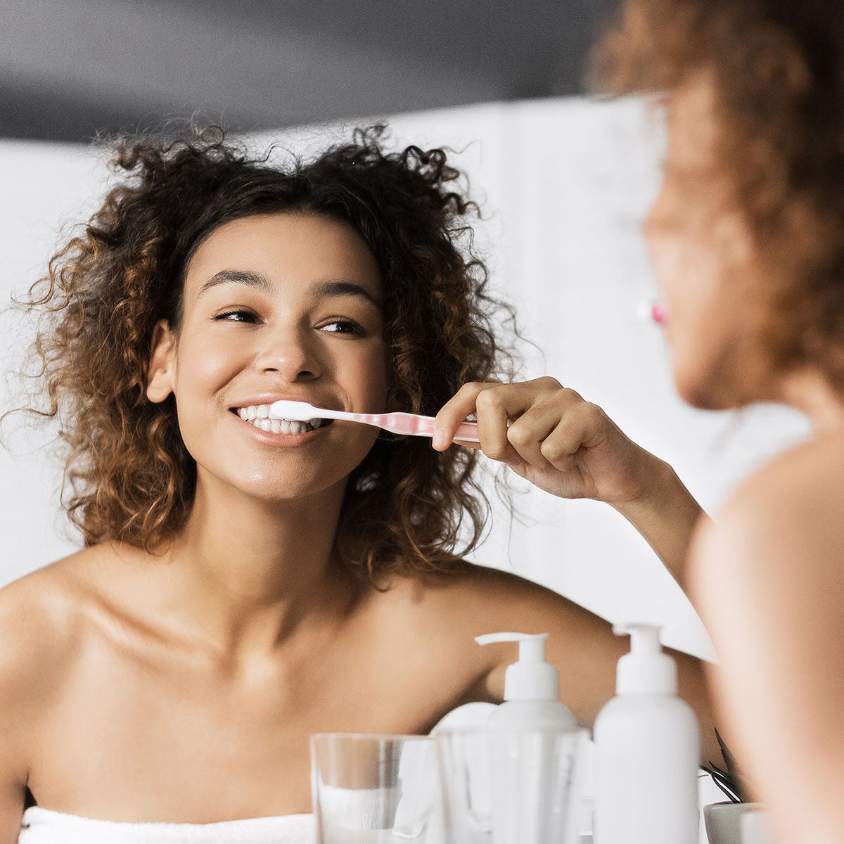 Woman cleaning her teeth in a mirror