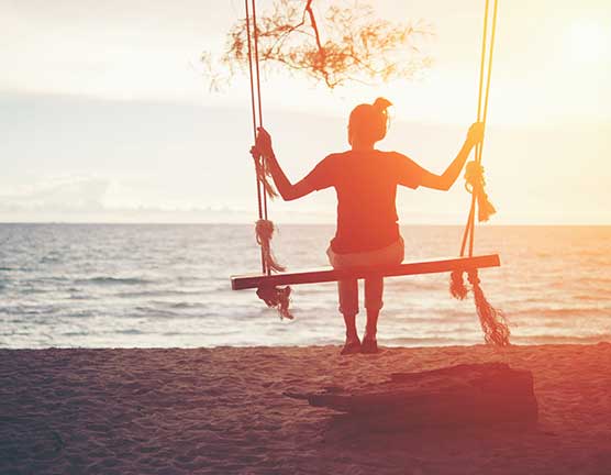 Woman on a swing looking out to sea